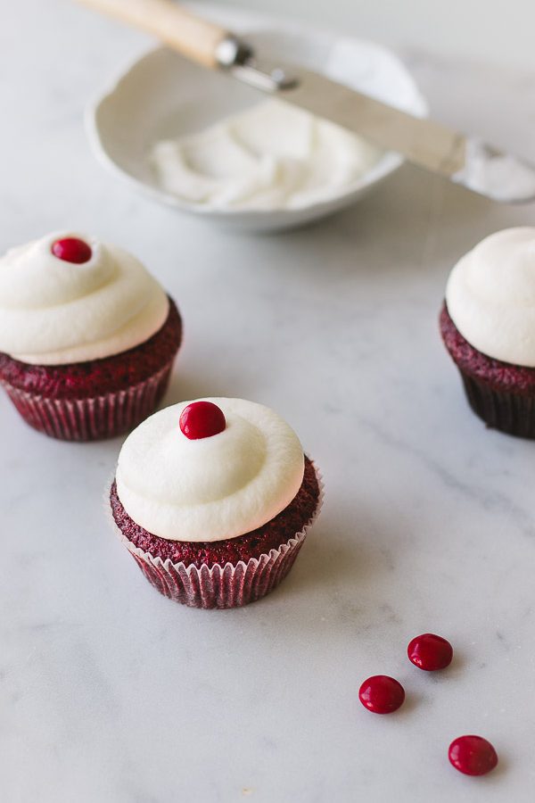 Red Velvet cupcakes with fluffy cream cheese frosting and red candy topping.