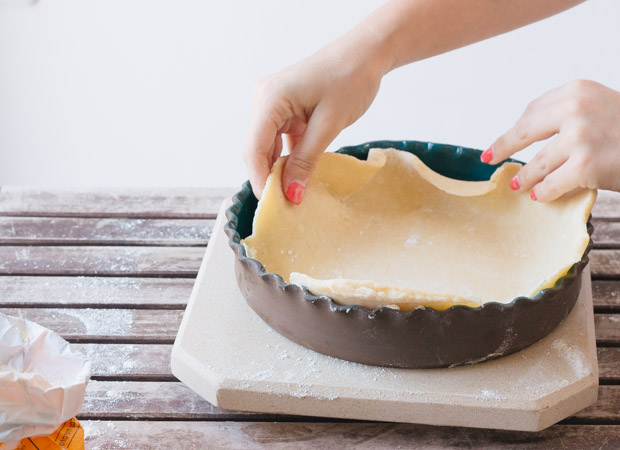 Hands laying pie dough into a pie pan.