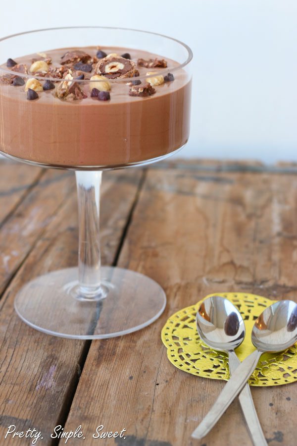 Nutella Mousse in a glass garnished with chocolate and hazelnuts.