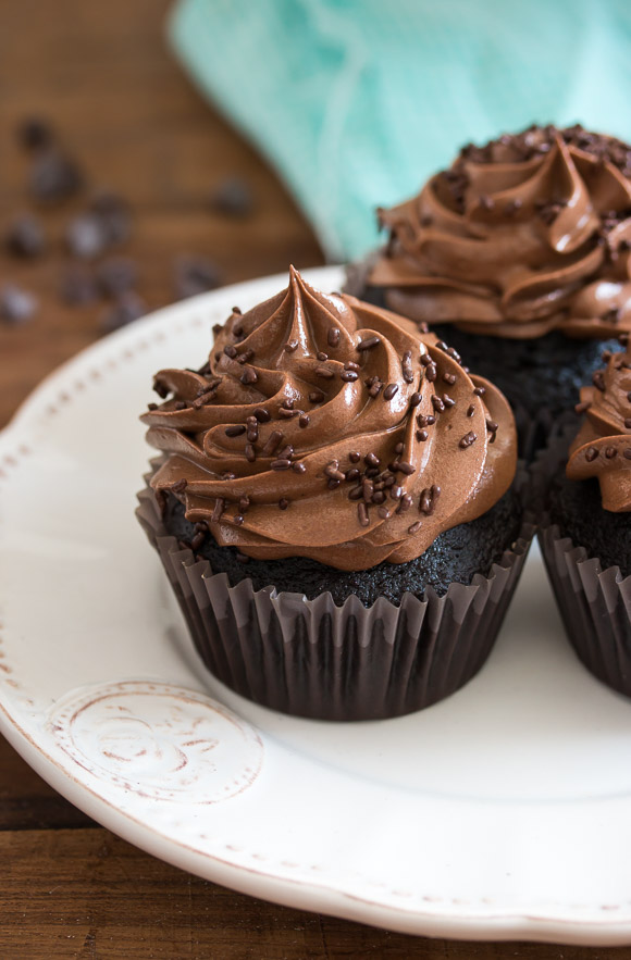 Each cupcake is in a dark brown paper liner, emphasizing the dark, moist cake visible at the base.