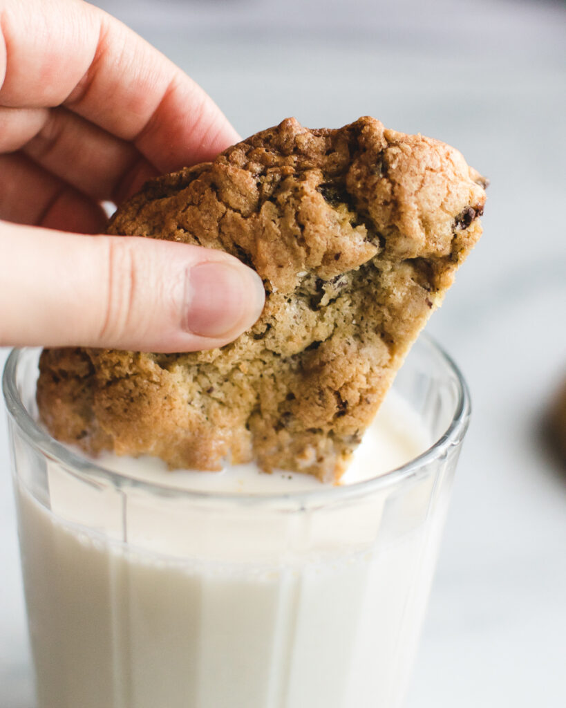 Dipping giant chocolate chip cookie into glass of milk.