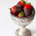 Chocolate covered strawberries in a silver pedestal bowl.