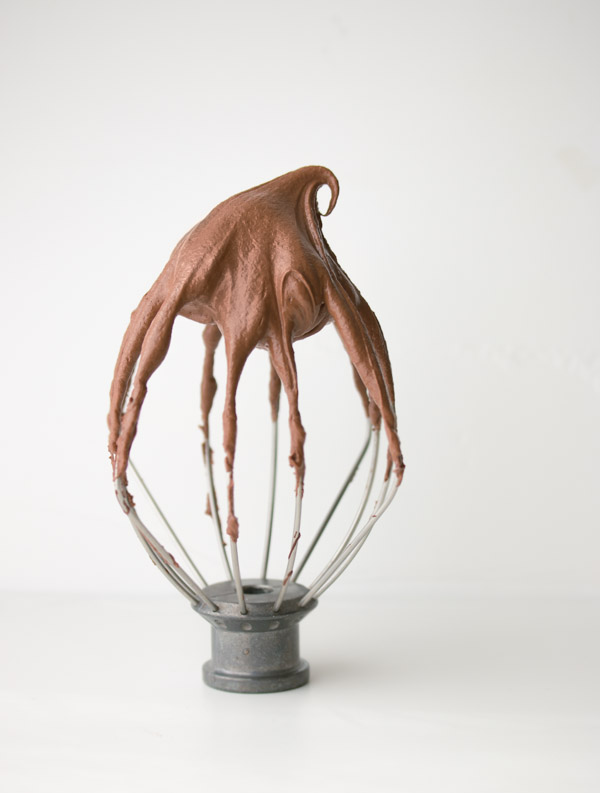 Perfect Chocolate Buttercream Frosting on an upside down stand mixer whisk, showcasing the perfect swirl.