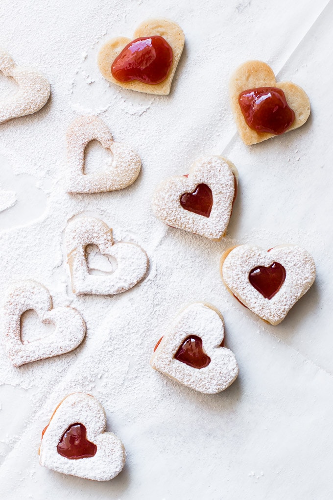 Linzer Cookie sandwiches shine with red filling from fruit jam centers.