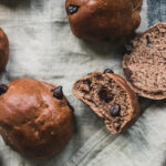 Fluffy chocolate flavored rolls, some split in half, with large chocolate chips.