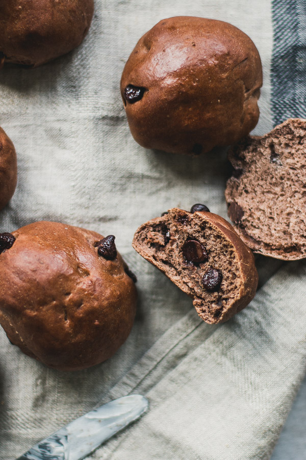 Fluffy chocolate flavored rolls, some split in half, with large chocolate chips.