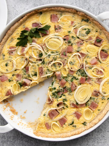 Ham and cheese quiche made with gruyere and swiss cheeses topped with thinly sliced leeks.