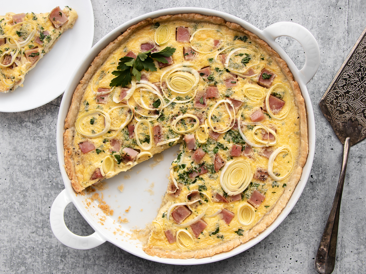 Ham and cheese quiche made with gruyere and swiss cheeses topped with thinly sliced leeks.