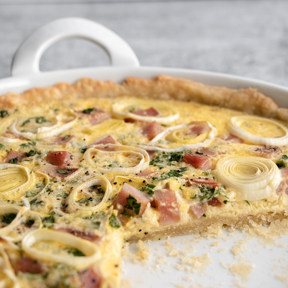 Fluffy and soft quiche made in a tart pan with ham, cheese, and onion.