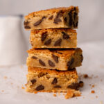 Chocolate chip cookie blondie bars with fudgy middles showing in a stack of four bars.