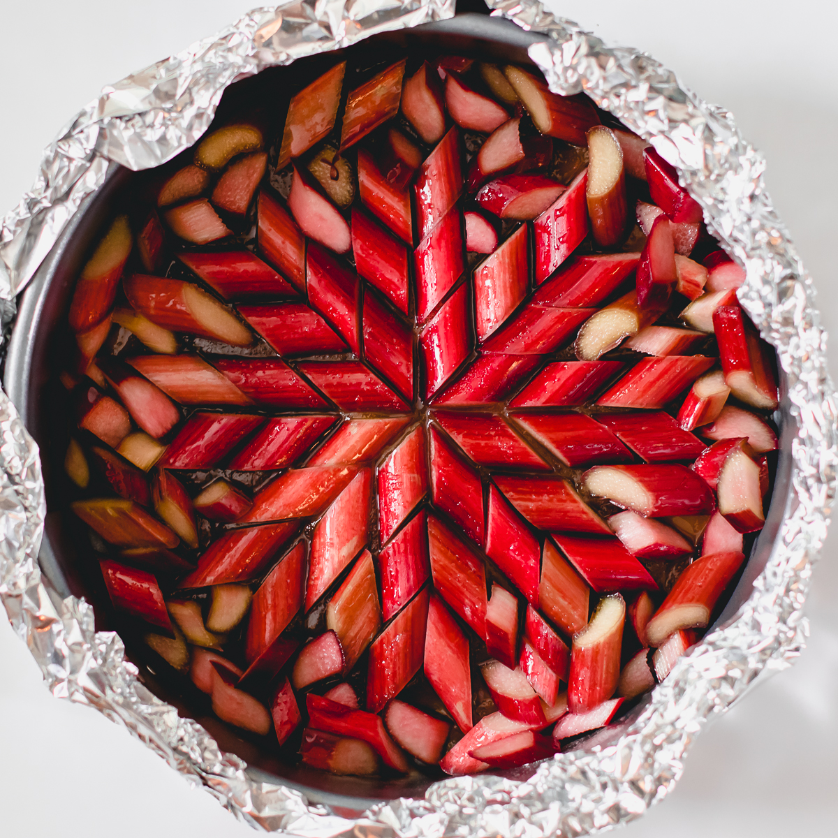 Rhubarb upside down cake first layer with ruby red rhubarb in a star-shaped quilting pattern radiating from the center.