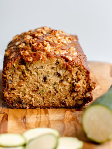 Zucchini maple nut bread with sliced zucchini in foreground.