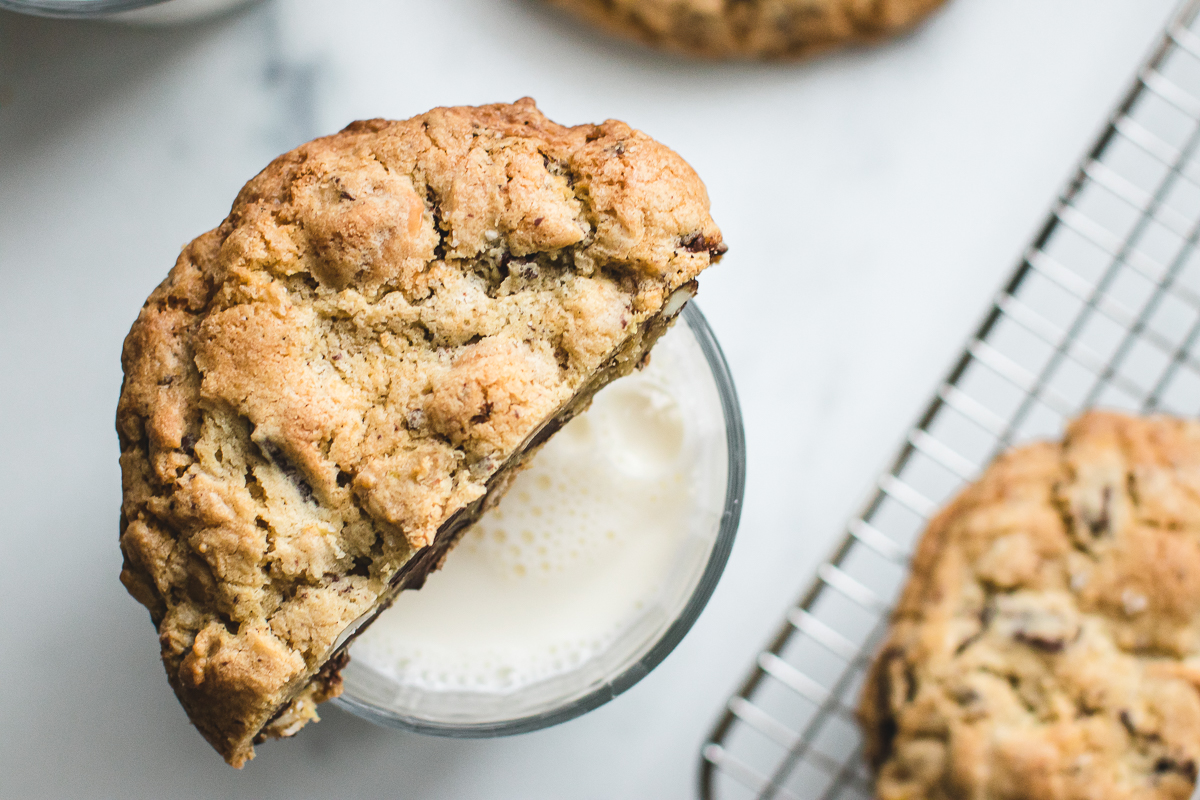 Giant Kitchen sink cookie over a glass of milk.