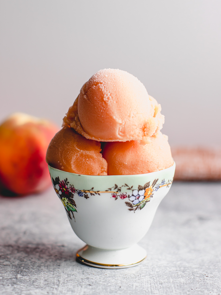 Scoops of frozen peach sorbet in a vintage teacup.