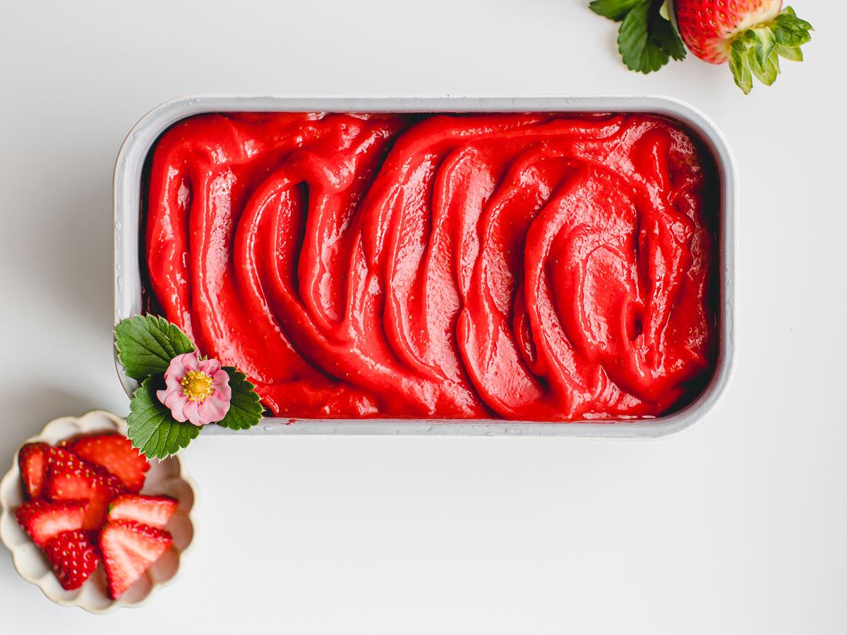 Luscious and velvety strawberry sorbet with a strawberry blossom and fresh strawberries.