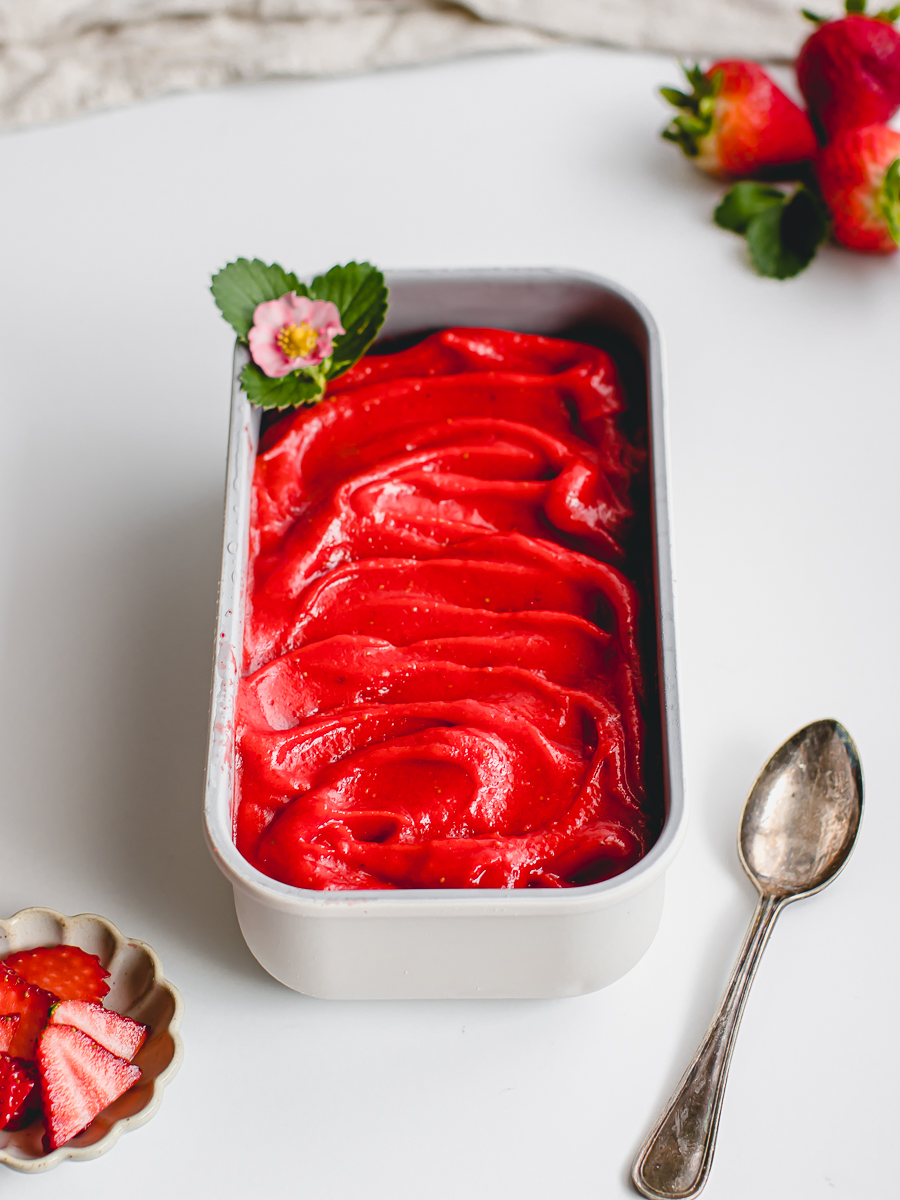 Luscious and velvety strawberry sorbet with a strawberry blossom and fresh strawberries.