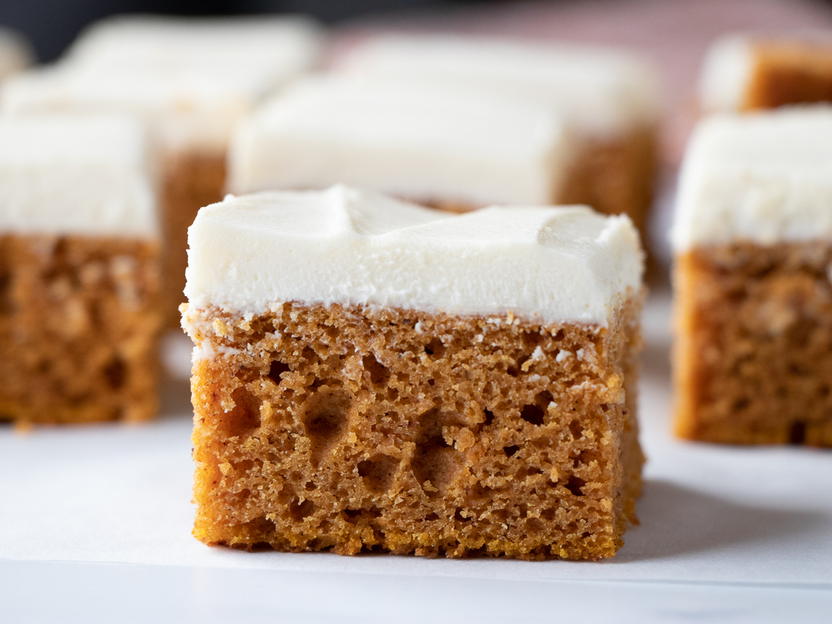 Closeup of a pumpkin bar with thick layer of tangy cream cheese frosting on top.